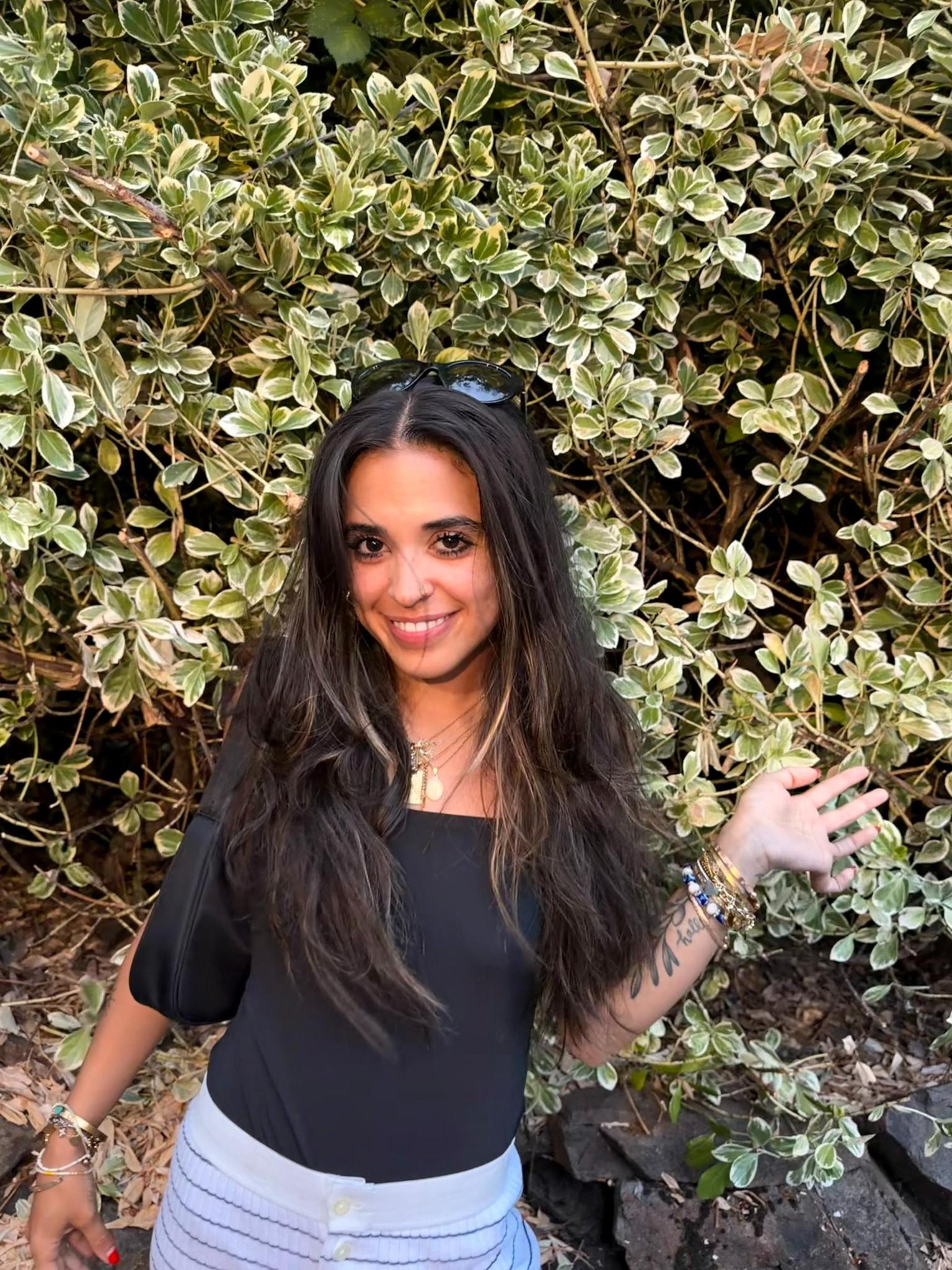 Corinn Gamez, founder of Start Biting, smiling outdoors in front of greenery.